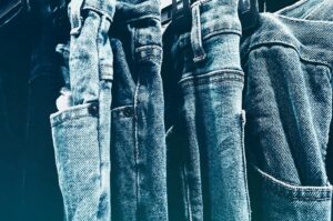 Close-up of denim jeans hanging on a rack, showing different washes and textures.