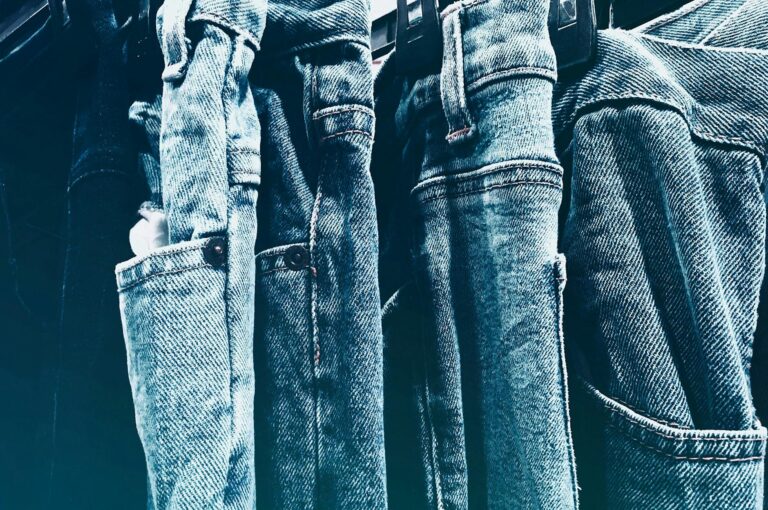 Close-up of denim jeans hanging on a rack, showing different washes and textures.
