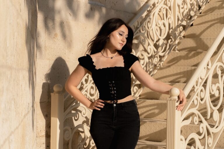 Petite woman wearing a fitted black cropped top with high-waisted black jeans, illustrating tops for petite women, flattering tops for short women, and tops that make petite women look taller.