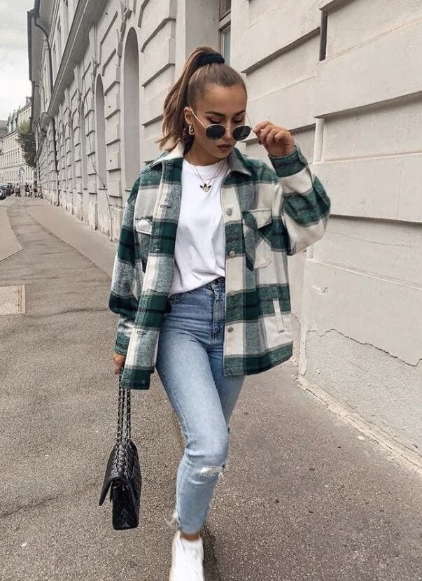 Woman wearing a green plaid shacket with a white T-shirt and jeans showing a classic plaid shacket outfit idea.