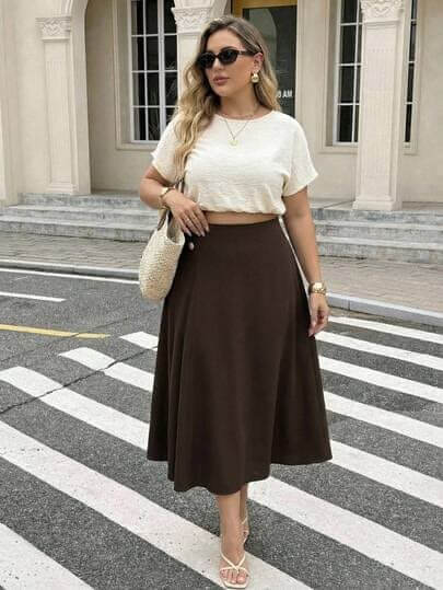 Woman wearing a high-waisted brown A-line skirt with a white top, showing high-waisted skirts for pear-shaped body.