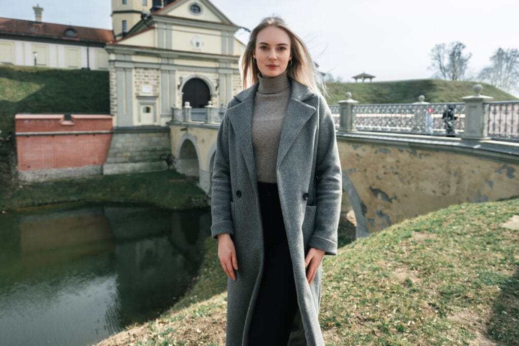 Woman wearing a gray trench coat with a black turtleneck and pants, showing how to style a trench coat for fall and seven fall outfits you can create with trench coat.