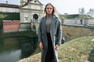 Woman wearing a gray trench coat with a black turtleneck and pants, showing how to style a trench coat for fall and seven fall outfits you can create with trench coat.