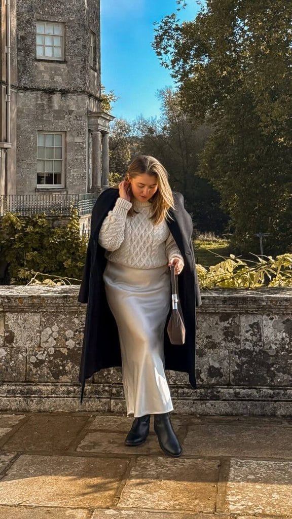 How to style a trench coat with a chunky knit sweater and satin midi skirt for fall.