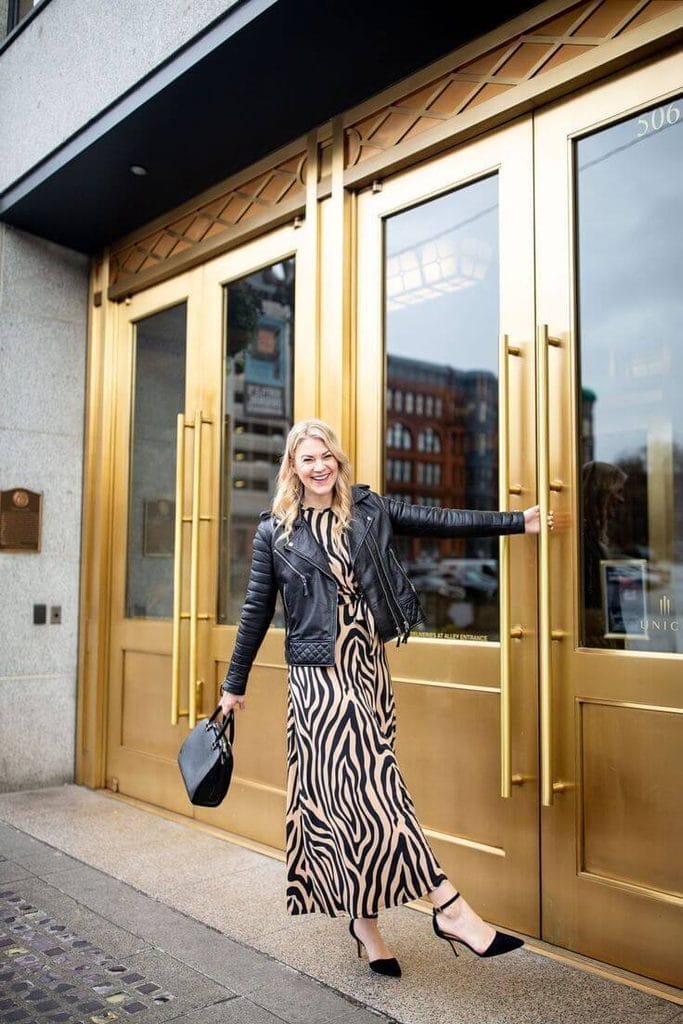How to style an animal print maxi dress with a black leather jacket, showing a zebra print dress layered with a leather jacket.