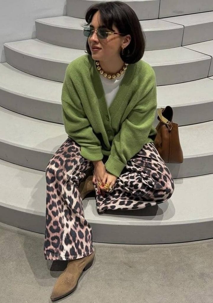 Woman wearing an olive green cardigan with leopard print pants, showing how to style emerald green and olive colors with animal print outfits.