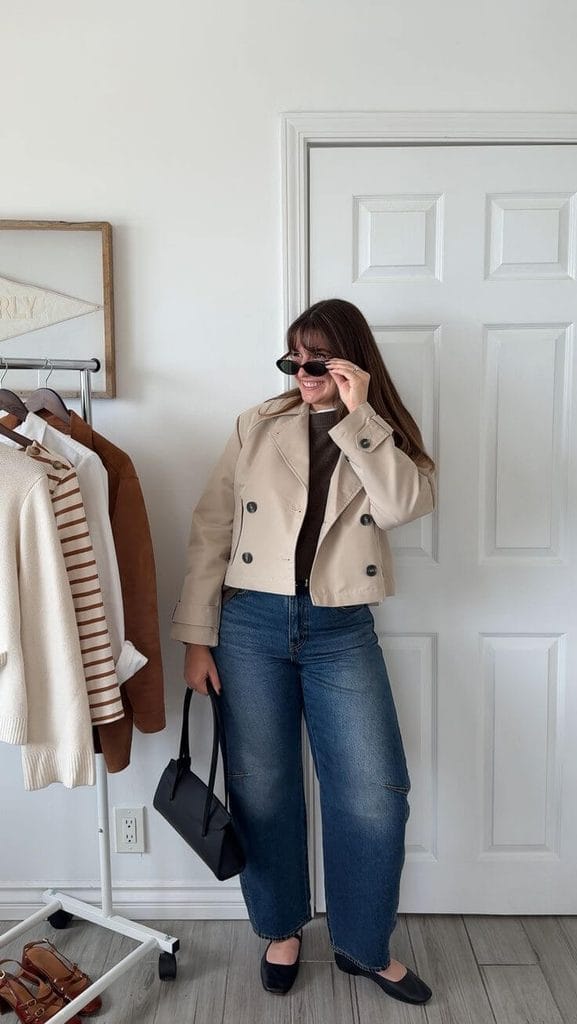 Woman wearing a cropped beige jacket with high-waisted jeans and black flats, talking about jackets for pear-shaped body.