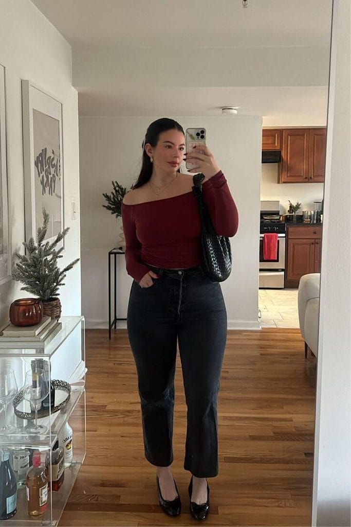 Woman wearing a burgundy off-shoulder top with black jeans and black heels, showing off-shoulder tops for pear-shaped body.