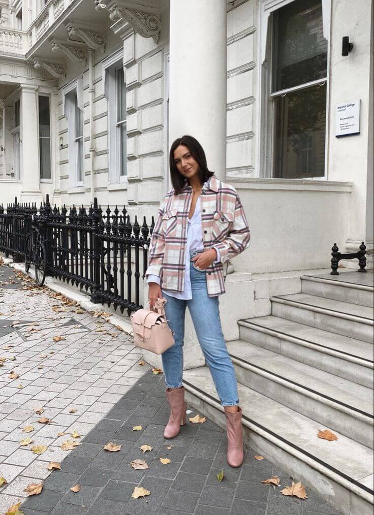 Woman wearing a pink plaid shacket over a light blue long-sleeved shirt with jeans and ankle boots for shacket outfit ideas.