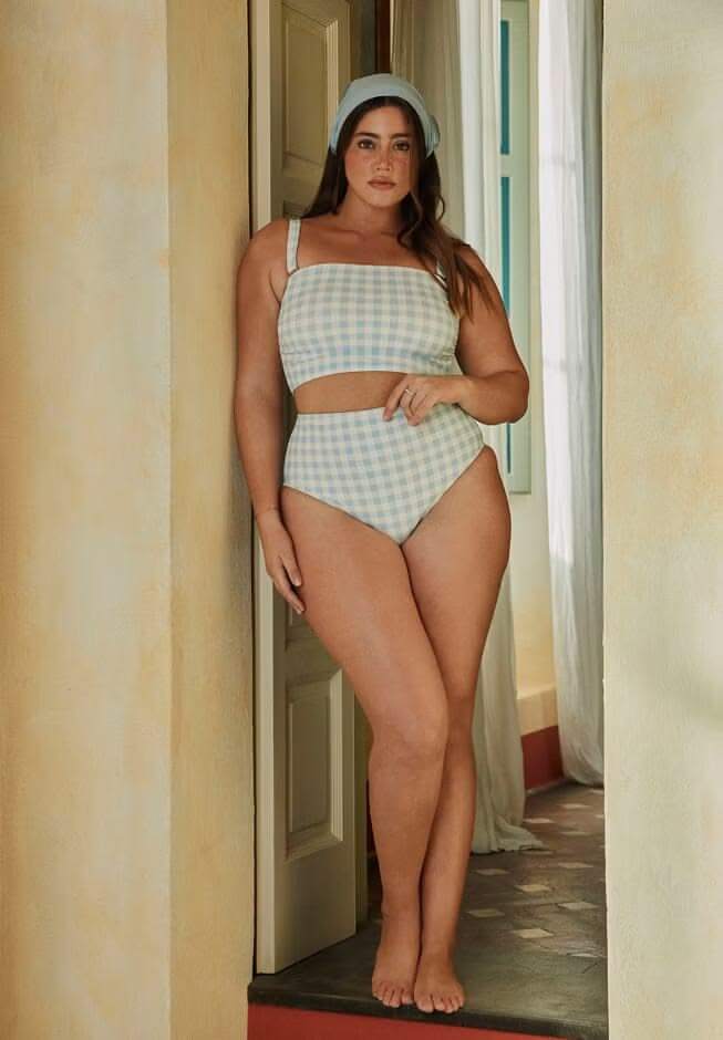 Woman wearing a blue and white checked two-piece swimsuit with a cropped top and high-waisted bottoms, featuring swimwear for pear-shaped body.