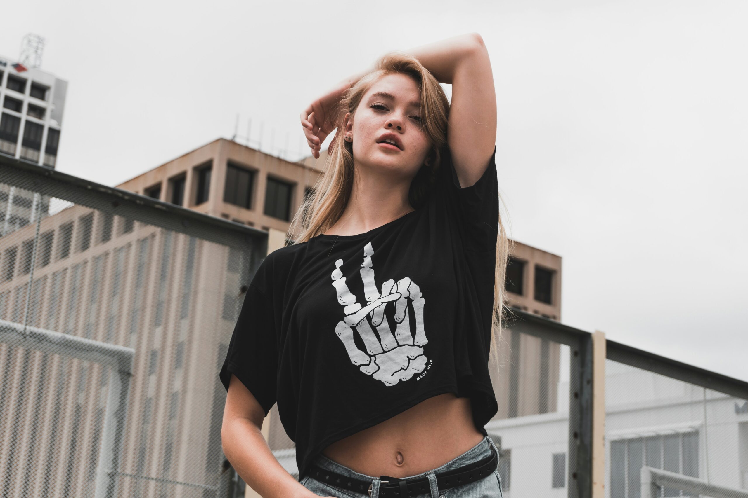 Woman wearing a black graphic Halloween T-shirt with a skeleton hand design, representing 13 Halloween T-shirt outfit ideas for women and ways to style Halloween T-shirts.