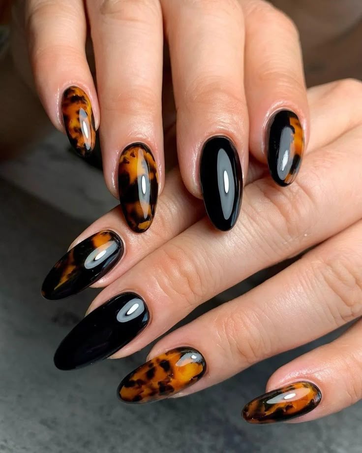 Glossy black nails paired with amber and dark brown tortoiseshell patterns on long almond-shaped nails, a stylish option for black tortoiseshell fall nails and fall nail ideas.