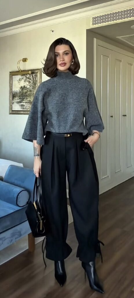 Woman wearing a black top, plaid cropped pants, and black shoes for a stylish cropped pants and sweater outfit for Thanksgiving dinner.