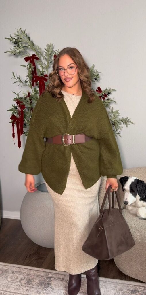 Dress and cardigan outfit for Thanksgiving dinner featuring a cream knit dress, an olive-green cardigan cinched with a brown belt, and brown knee-high boots, styled with a matching brown handbag.