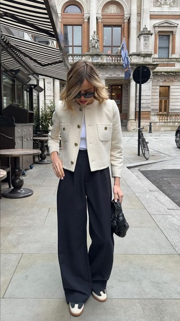 Woman wearing a white T-shirt with high-waisted black wide-leg trousers and a cropped cream tweed jacket, showing how to style a Halloween T-shirt with wide-leg trousers and a tweed jacket.