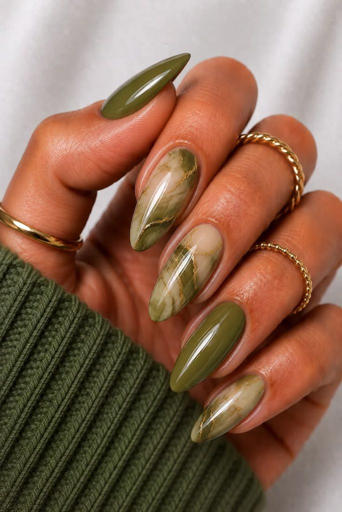 Close-up of long almond-shaped nails featuring glossy olive green polish paired with translucent olive green marble nail art and delicate gold veining. These olive green marble nails are an elegant choice for fall nail ideas.