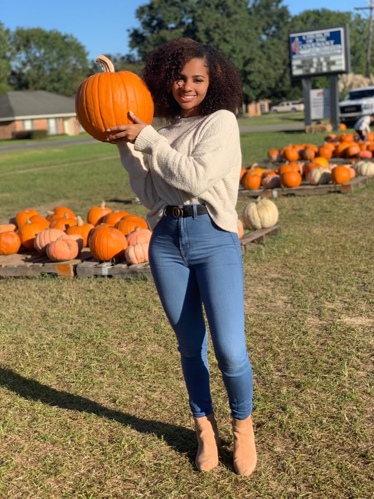 Pumpkin patch outfit featuring a cream sweater, blue jeans, and tan ankle boots, showing a cozy sweater and jeans outfit for pumpkin patch visits.