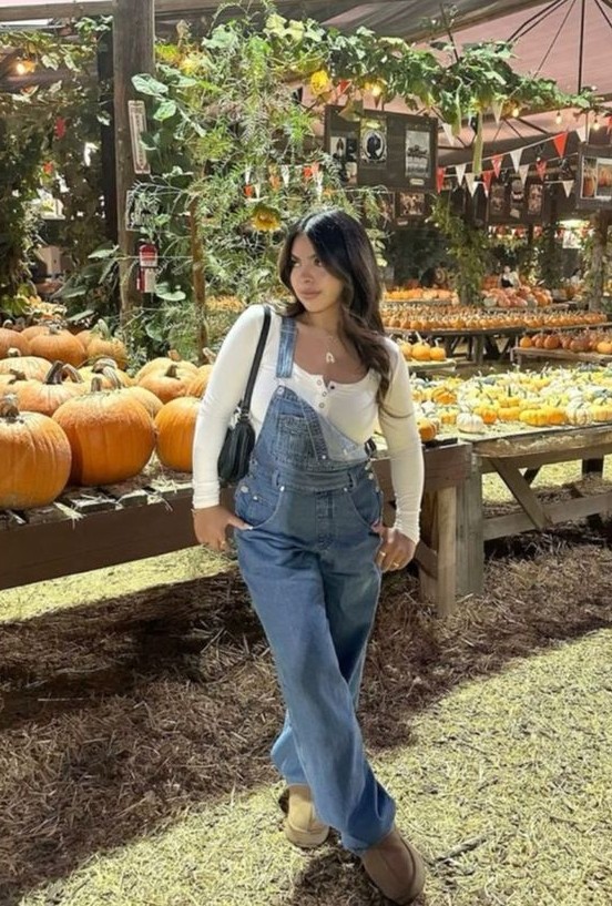 Pumpkin patch outfit with denim overalls and a fitted white long-sleeve top, styled with casual shoes for a relaxed fall look while visiting a pumpkin patch.